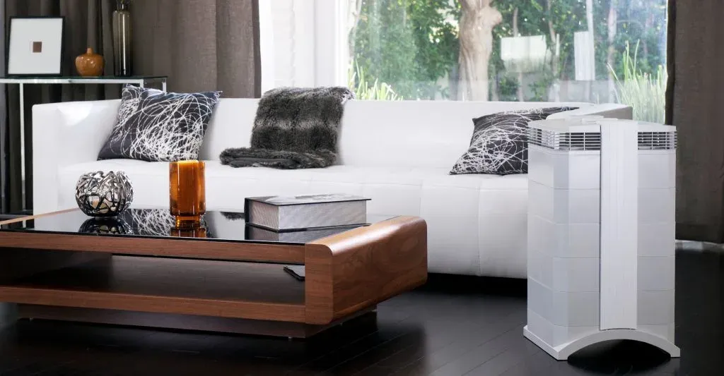 White air purifier standing beside a white sofa and wooden coffee table in a modern living room