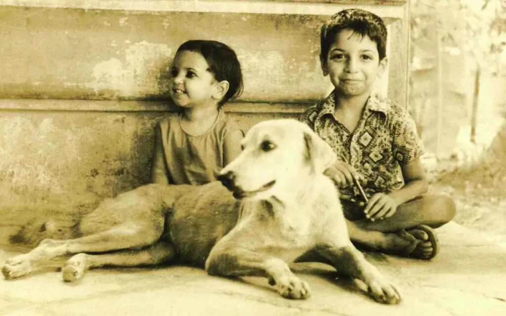 Sepia-toned old photograph of two young children sitting beside a resting dog