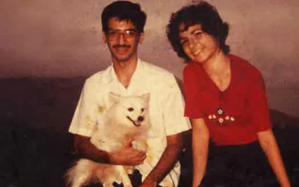 Vintage photo of a young man and woman kneeling together with a small white dog
