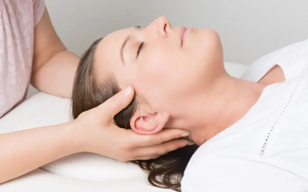 Therapist cradling a relaxed woman's head during a craniosacral treatment session
