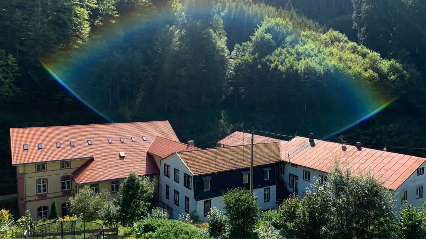 red roofed buildings below forested hillside