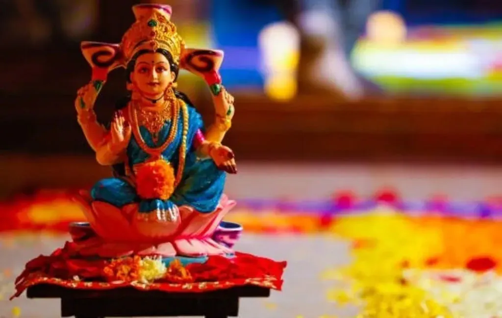 Ornate idol of the goddess Laxmi seated on a lotus amid colourful festival flowers