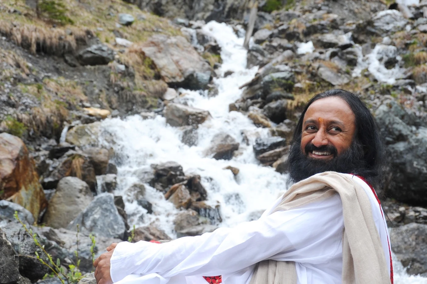 Gurudev standing by a mountain stream on the drive down from Arosa, posing for the camera