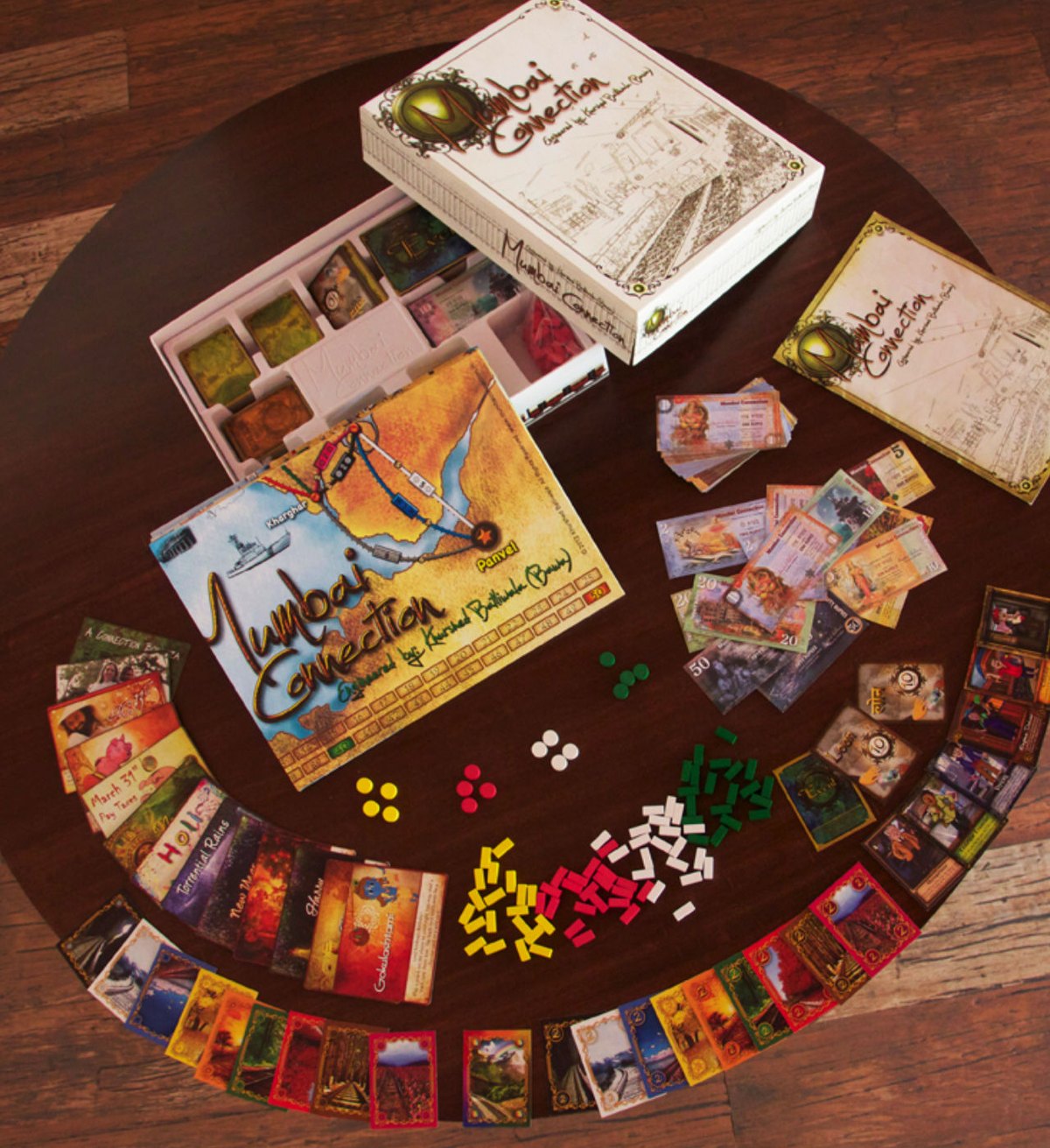 The Mumbai Connection components laid out on a wooden table: the board, cards, wooden track markers and money