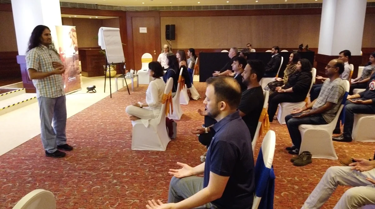 A corporate group meditating led by Dinesh
