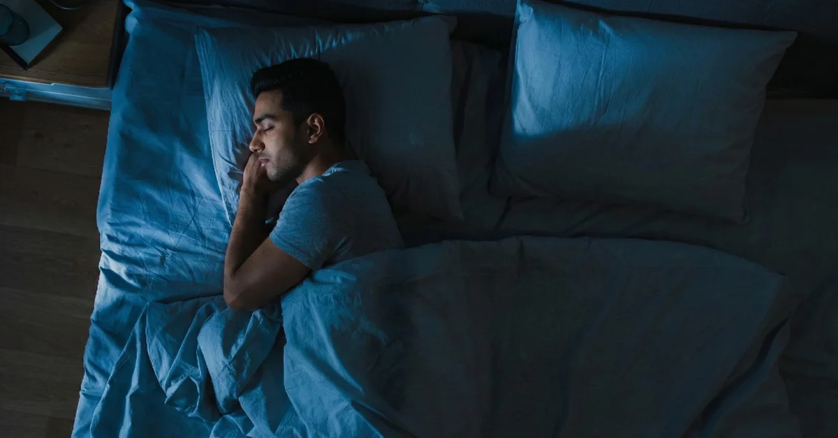 A man asleep in a dark bedroom
